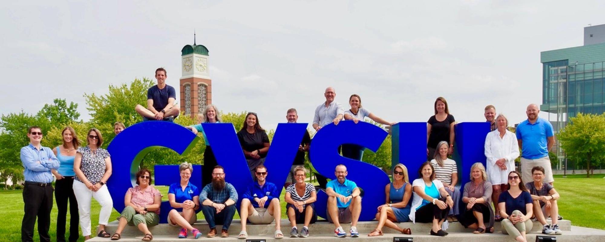 The department of movement science faculty and staff posing in front of the GVSU letters.